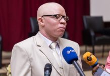 Dr Hakizimana presenting his new Christian book to believers